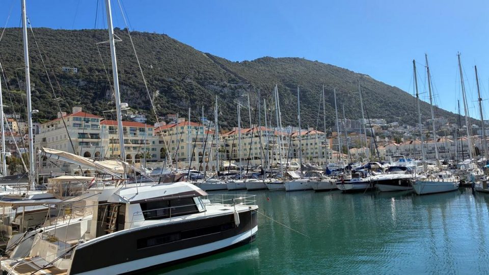 Queensway Quay Marina in Gibraltar with luxury yachts, waterfront apartments, and views of the Rock under a clear blue sky.