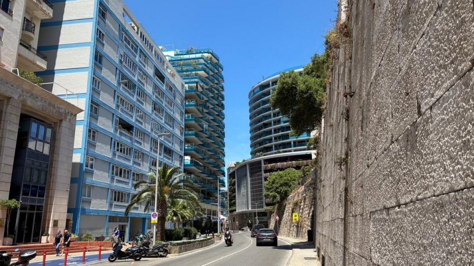 Modern apartment buildings near Ocean Village Gibraltar with palm trees, contemporary architecture and an urban streetscape beneath the Rock of Gibraltar.