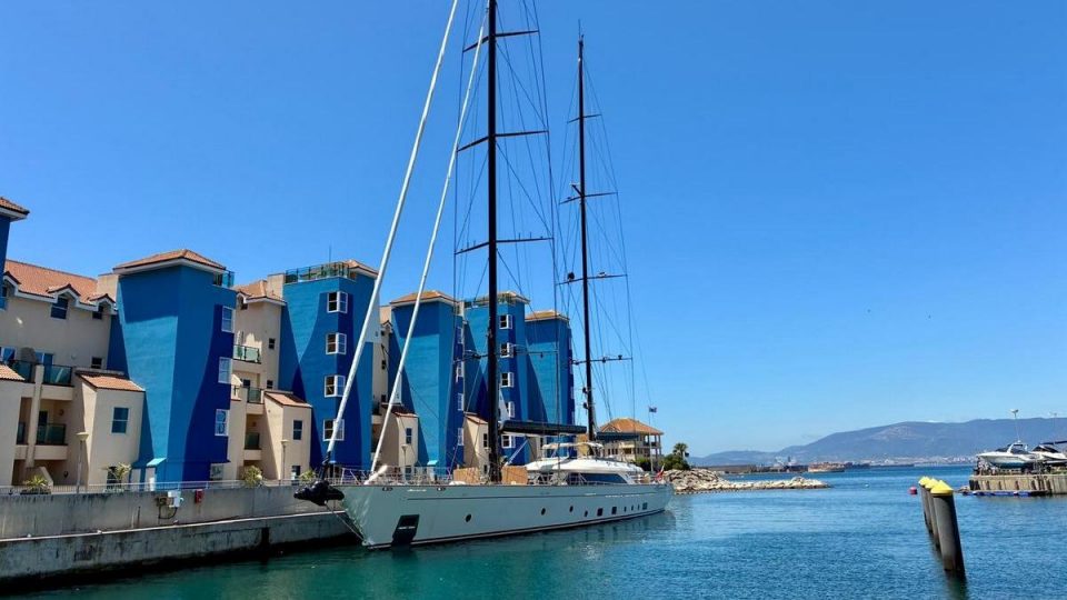 Gibraltar Marina Waterfront Lifestyle Luxury yacht moored in Gibraltar marina with waterfront apartments and Mediterranean views on a sunny day.